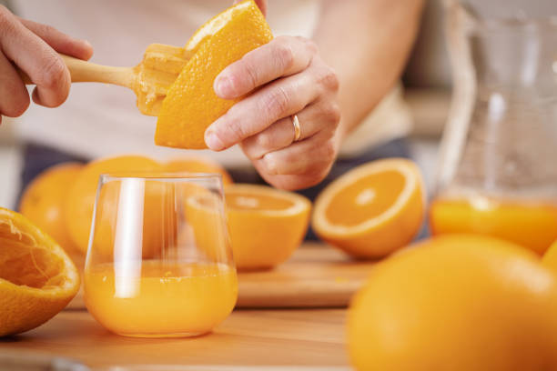 Front view of an unrecognizable man squeezing an orange to make juice
